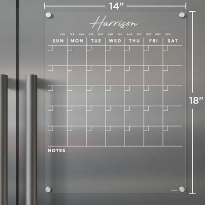 The Clear Acrylic Monthly Fridge Calendar by Girl Friday features a white grid and text on gray, is designed for wet-erase markers, and includes Harrison at the top with space for notes below. It measures 14x18 inches.