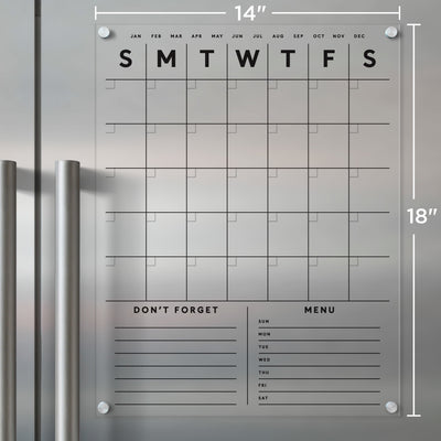 The Girl Friday Shop Clear Acrylic Fridge Calendar features a detachable design with customizable bottom sections. It displays weekdays at the top and months above. Includes Dont Forget and Menu sections with daily lines, usable with wet-erase markers, and easily mounts in corners like a wall calendar.