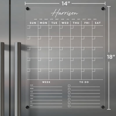 The Girl Friday Clear Acrylic Monthly Fridge Calendar, 14x18, features customizable bottom sections with weekday grids labeled Week and To Do. Elegantly mounts near fridge handles, perfect for wet-erase notes. Add your family name for a personalized touch.