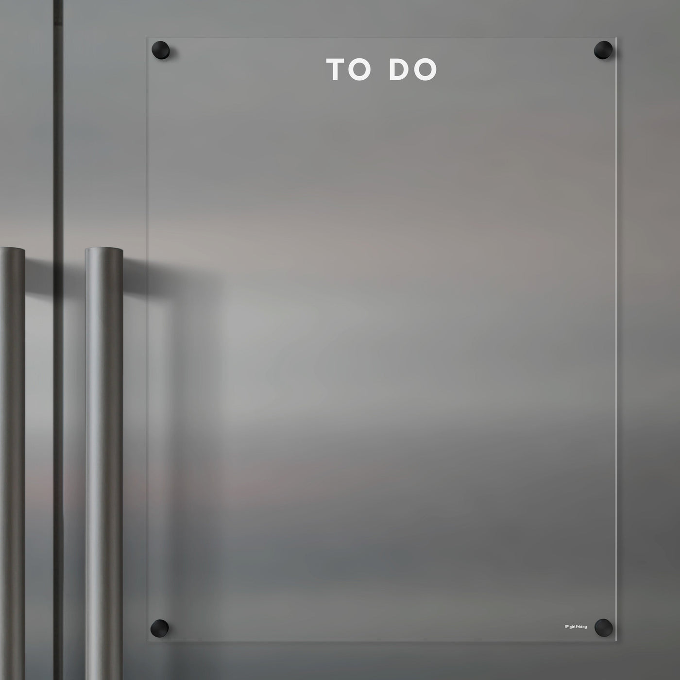 The Girl Friday Clear Acrylic Fridge To Do List features white text and mounts on metallic surfaces. It has two vertical metal handles on the left, perfect for quick updates with wet-erase markers.