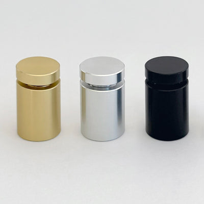 Three gold, silver, and black cylindrical containers are arranged side by side on a plain background. Their metallic finishes pair elegantly with Girl Friday Shops Please Remove Your Shoes acrylic sign. Each container has a matching reflective lid that enhances the sleek ensemble.