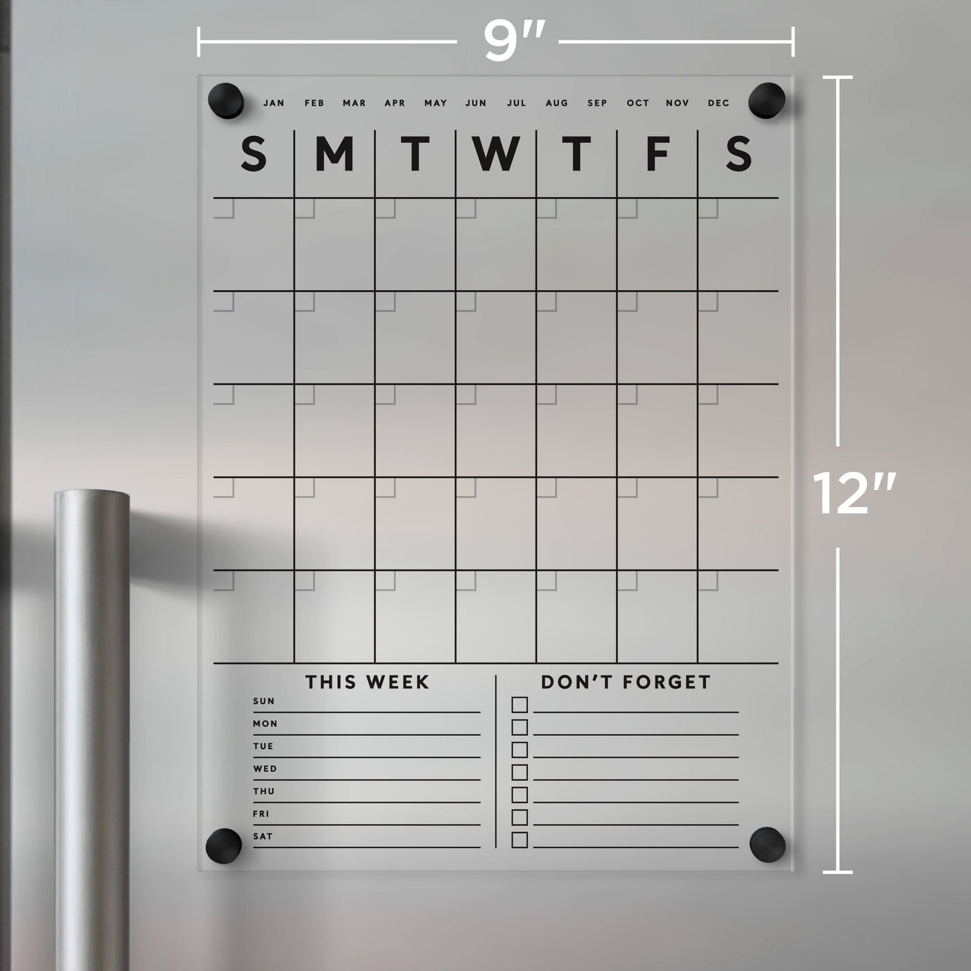 The Clear Acrylic Monthly Magnetic Fridge Calendar by Girl Friday Shop, measuring 9x12 inches, has a grid layout with months, This Week, and Dont Forget sections. With black text and small black mounting circles in the corners, its perfect for dry-erase markers.
