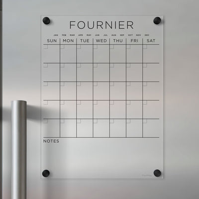 The Clear Acrylic Monthly Magnetic Fridge Calendar | Custom Family Name by Girl Friday is a transparent, customizable calendar with labeled months and days. It has sections for daily plans, a Notes area, and mounts to metallic surfaces, ideal for wet-erase markers.