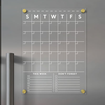 The Girl Friday Shop offers a Clear Acrylic Monthly Fridge Calendar that easily attaches to metallic surfaces. It features customizable bottom sections, is designed for use with wet-erase markers, and provides a sleek, transparent design perfect for quick updates.