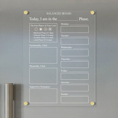 The Balanced Beyars Weekly Phase Board by Girl Friday is a clear acrylic planner ideal for tracking menstrual cycles, featuring weekday columns and sections for emotional/physical feelings. It includes supportive strategies and diagrams of the menstrual, follicular, ovulatory, and luteal phases.