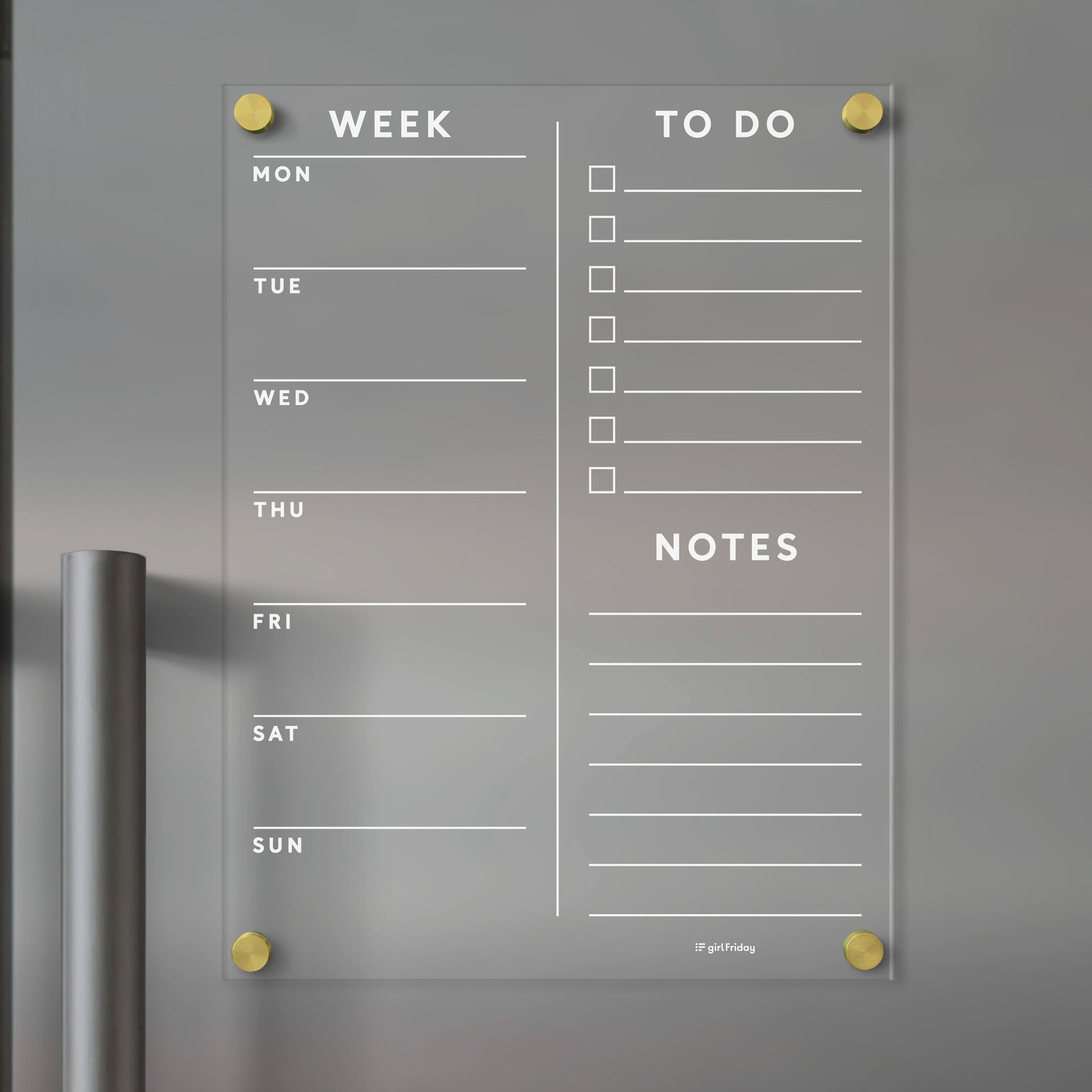 The Girl Friday Acrylic Fridge Planner, mounted with gold standoffs, offers customizable daily sections, a to-do list with checkboxes, and a notes area. Ideal for dry-erase markers, it features a slight metallic hint on the left side.