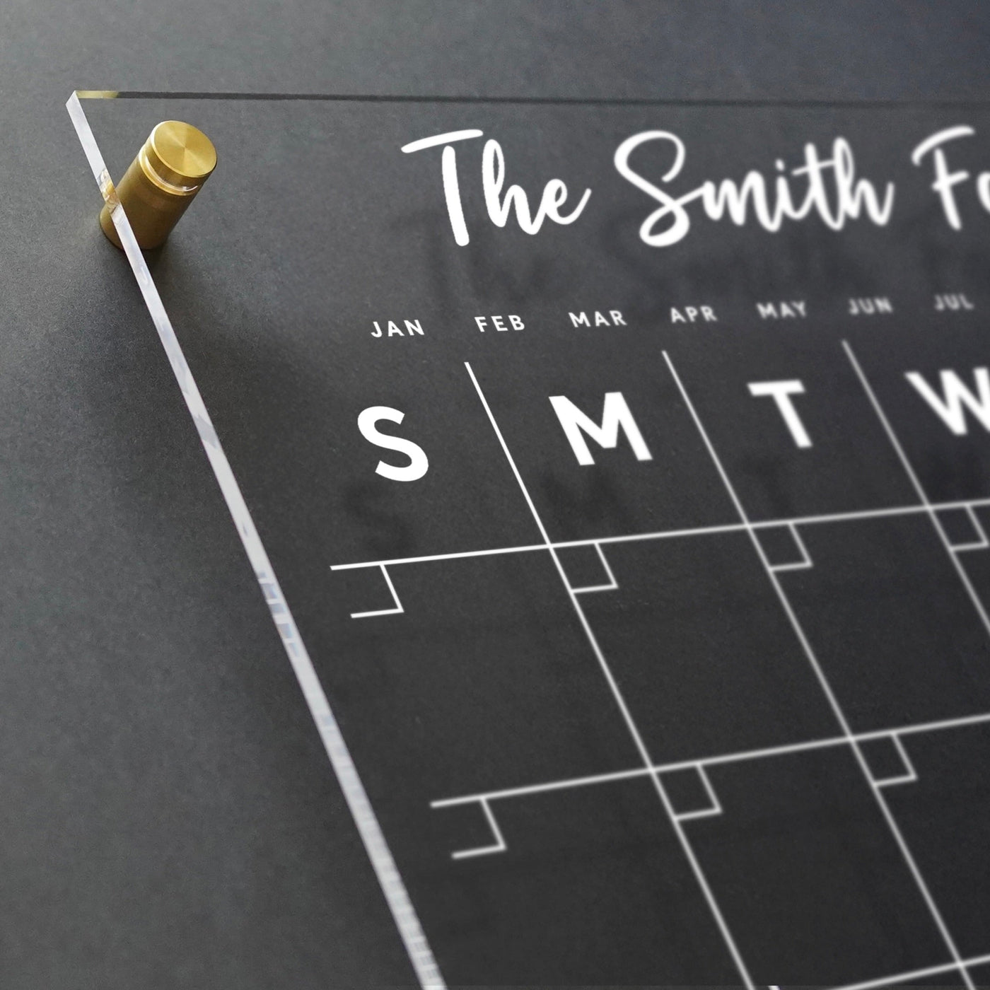 The Girl Friday Shop offers a high-quality clear acrylic monthly wall calendar with white font and 2 customizable sections. Days are abbreviated as S, M, T, W, T, F, S and it works well with wet-erase markers for personalized planning.