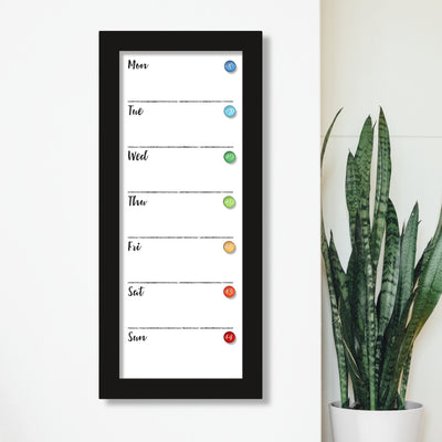 The CalendarGirlCompany #921 9 x 24 weekly whiteboard calendar is wall-mounted with a premium acrylic finish, featuring a sleek Monday-to-Sunday vertical layout and colorful magnets. Its paired with a tall green plant in a white pot on a light backdrop, perfect for chalk ink markers.