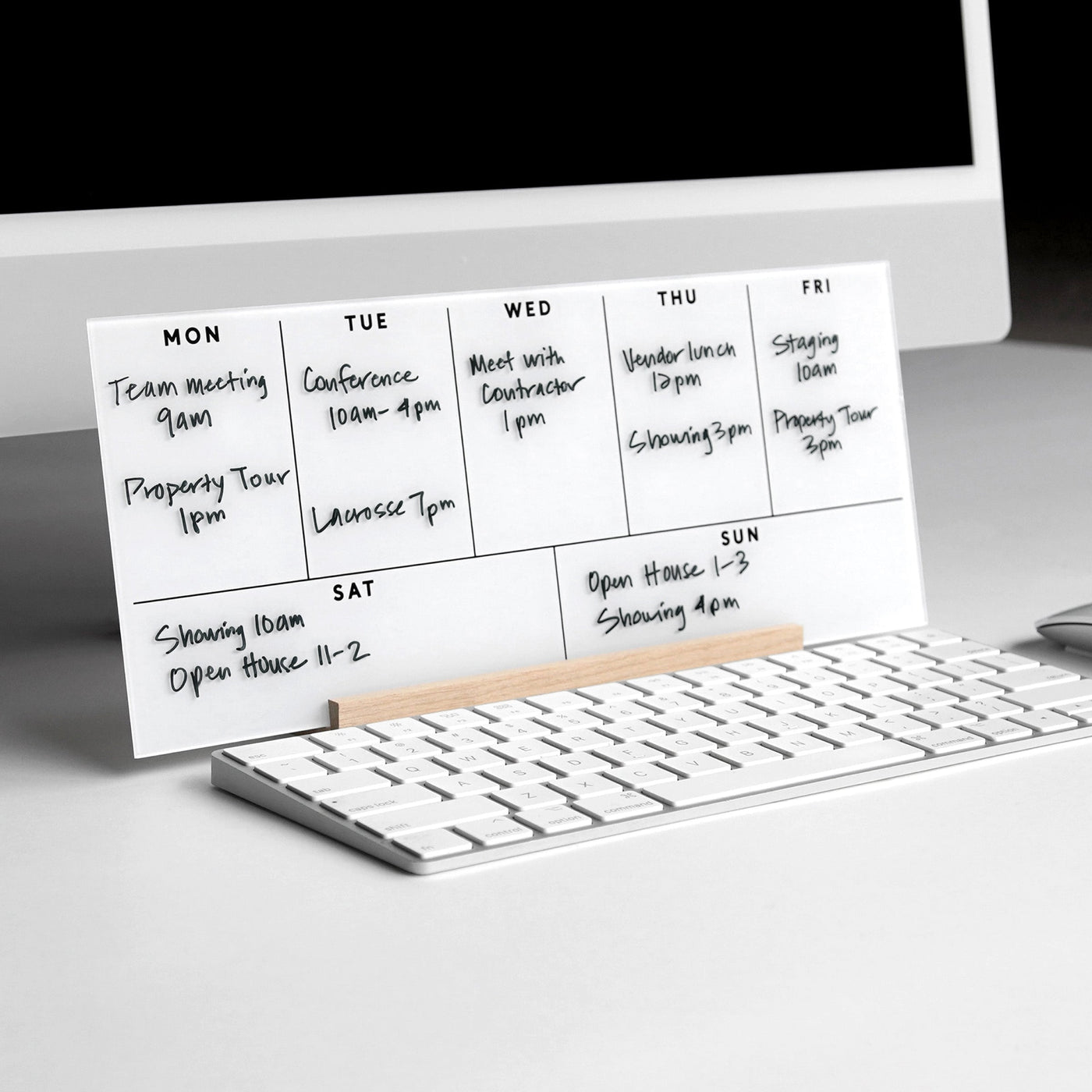 The Girl Friday Weekly Acrylic Calendar with Wood Stand is a minimalist desk accessory that serves as a whiteboard planner. Placed in front of your monitor and keyboard, it neatly displays your weekly schedule of meetings, tours, and events.