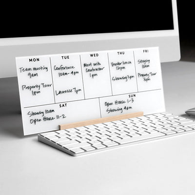The Girl Friday Weekly Acrylic Calendar with Wood Stand is a minimalist desk accessory that serves as a whiteboard planner. Placed in front of your monitor and keyboard, it neatly displays your weekly schedule of meetings, tours, and events.