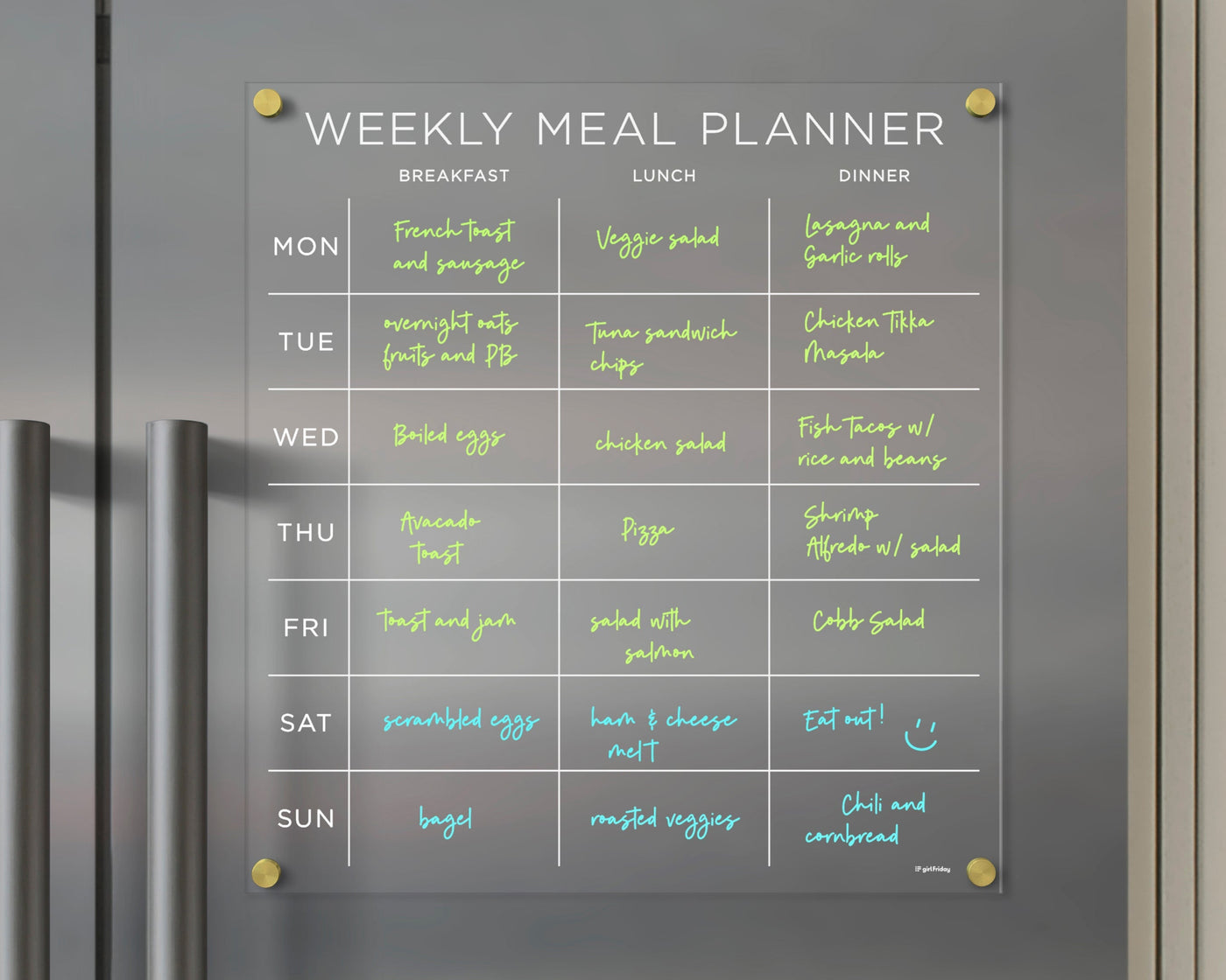 The Girl Friday Shops Clear Acrylic Fridge Meal Planner is a magnetic tool for weekly meal organization. With neon text on a grey background, it includes options like bagels and salads. Update plans daily with wet-erase markers for breakfast, lunch, and dinner.