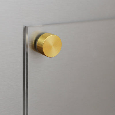 A close-up shows a glass sheet on a metallic surface secured by a round, brushed gold knob. The slightly opaque glass complements the smooth silver texture, reflecting the modern elegance of tracking physiological changes on your Girl Friday Balanced Beyars Weekly Phase Board.