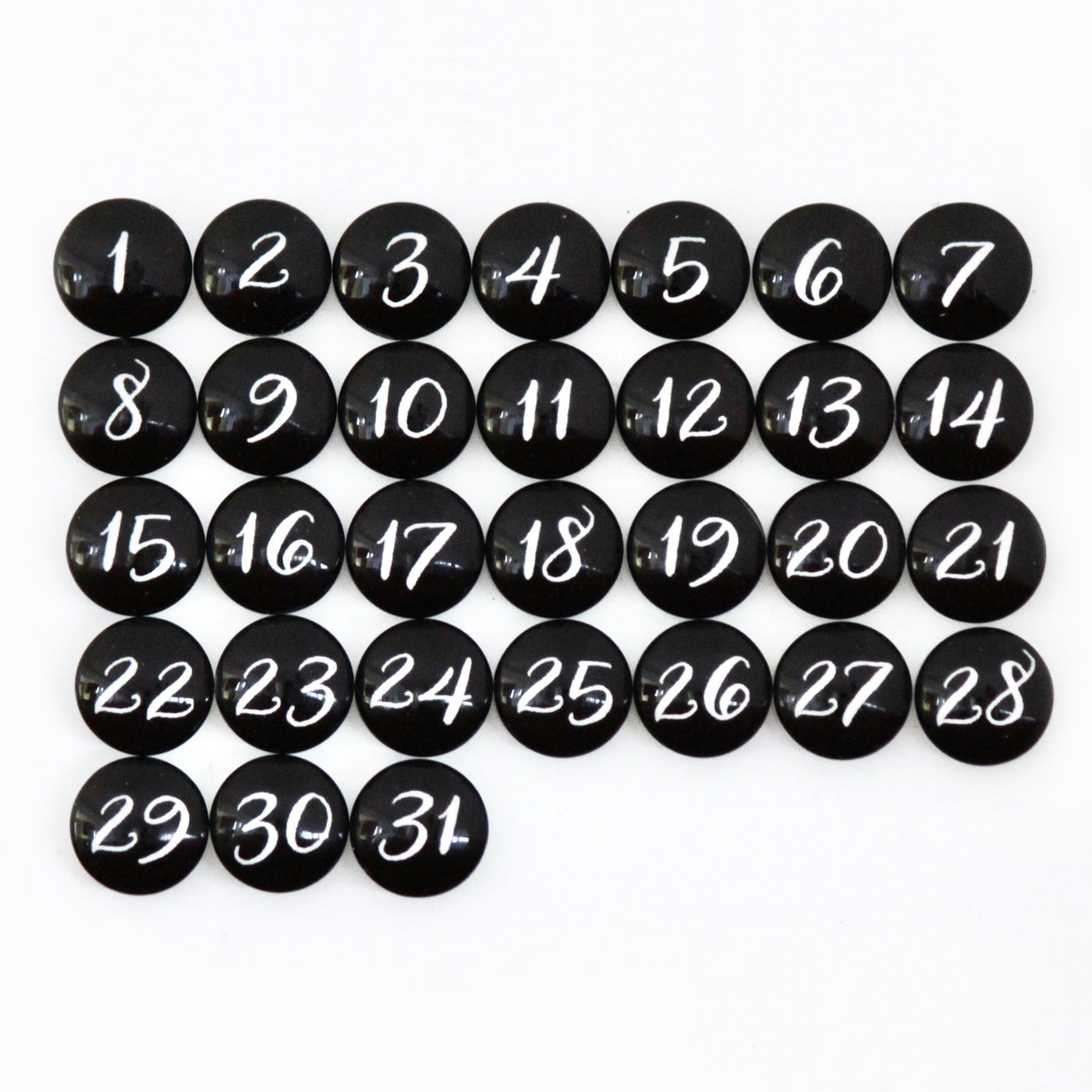 Black circular magnets numbered 1-31 in white script are arranged on a grid pattern against the premium CalendarGirlCompanys 24 x 18 Framed Whiteboard Calendar.