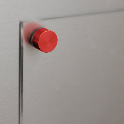 A close-up of a minimalist door hinge with a bright red knob complements the sleek metallic door panel, while the brushed steel finish pairs effortlessly with the Clear Acrylic Fridge Planners customizable title by Girl Friday, enhancing the contemporary aesthetic.