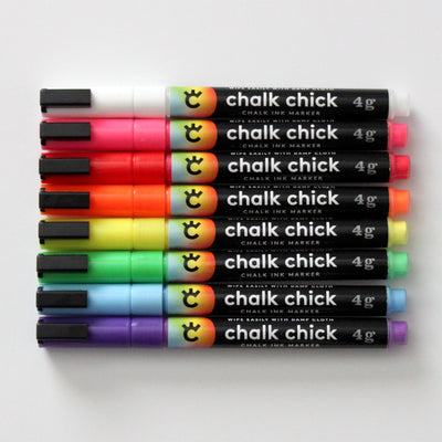A set of ten horizontally arranged Chalk Ink Colored Markers, brand named Girl Friday Shop, feature an array of colors like black, white, and red. Ideal for acrylic boards, each fine-tip marker weighs 4g.
